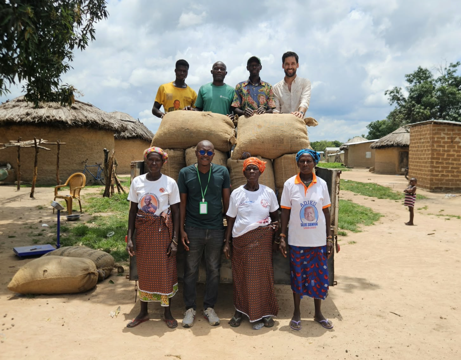 Women cooperative members and Ivoire Essentials sourcing team standing in front of a truck loaded with 80 kg bags of shea nuts in a village in Côte d’Ivoire